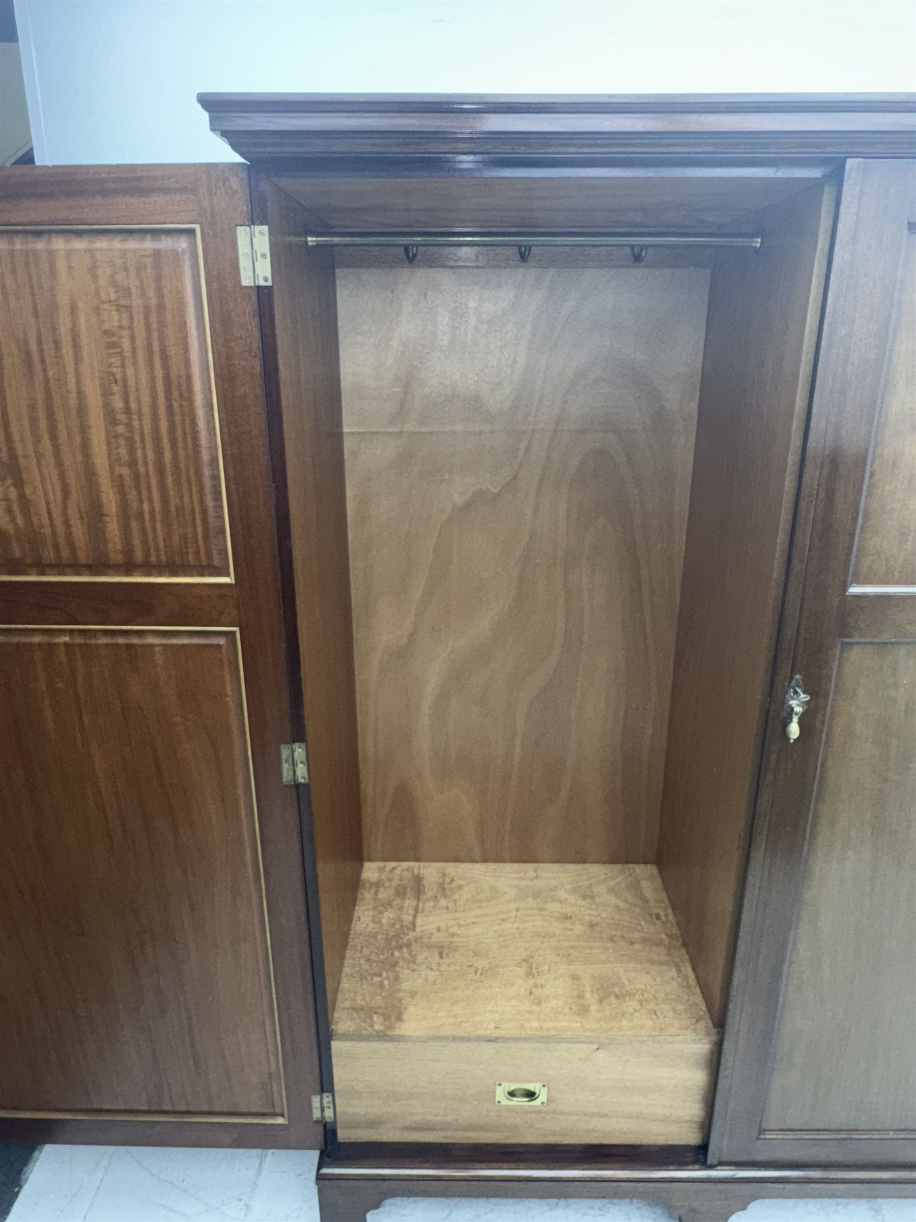 Wylie & Lochhead, Glasgow - early 20th century mahogany and satinwood double wardrobe, projecting cornice over panelled doors, interior fitted with mirrored door, shelves, drawers, hooks and hanging rail, raised on bracket supports with ceramic castors