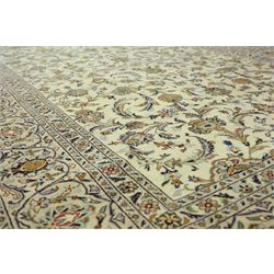 Central Persian Kashan carpet, ivory ground, field with an all-over design of scrolling palmettes and floral sprays in blue and terracotta within a beige ground and pale blue floral border