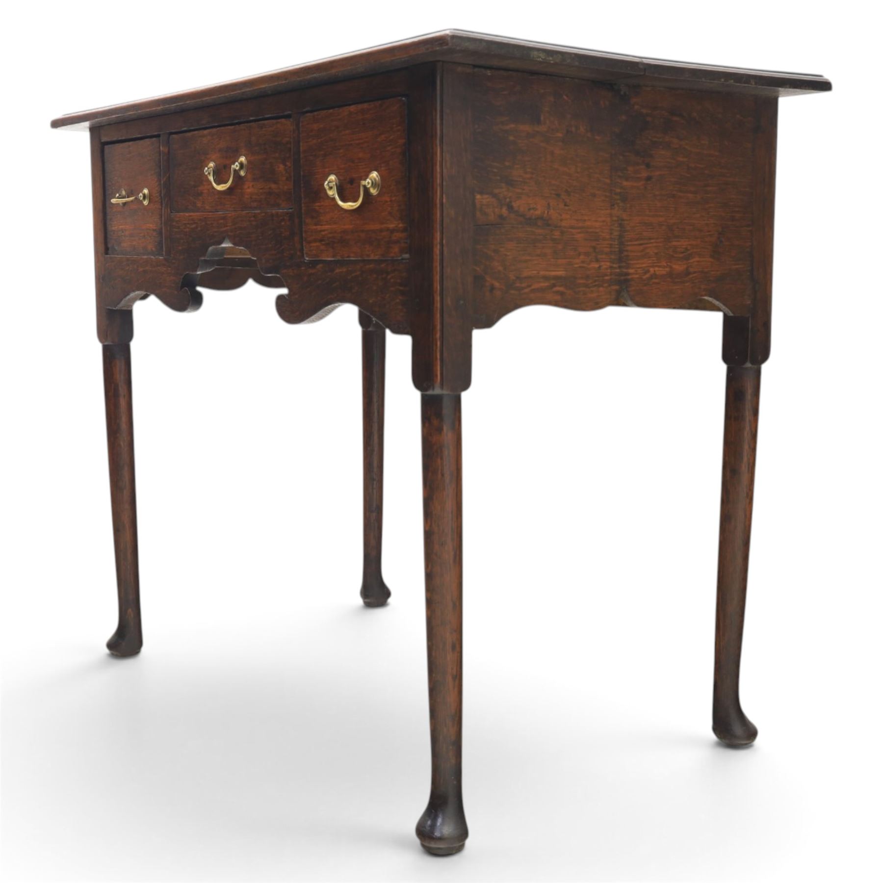 18th century oak lowboy, rectangular plank top with moulded edge, above three assorted drawers with brass swan neck handles, shaped apron raised on pad feet