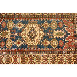 Caucasian hand-knotted runner, dark navy ground with three ivory geometric medallions surrounded by stylised flowerheads and angular motifs in madder red, green and ivory, enclosed by repeating geometric borders