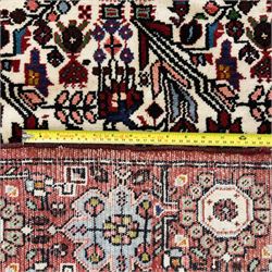 North west Persian Rudbar hand-knotted rug, ivory field woven with a repeating pattern of stylized shrubs, rosettes, and geometric floral motifs in tones of madder red, turquoise, indigo, and ochre, enclosed by a border of linked rosettes and angular flowerheads between narrow guard stripes 