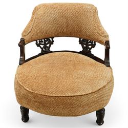 Late Victorian mahogany framed tub shaped chair, curved padded back and overstuffed seat in textured ochre fabric, pierced mahogany back supports with foliate and scroll carving, on turned front legs