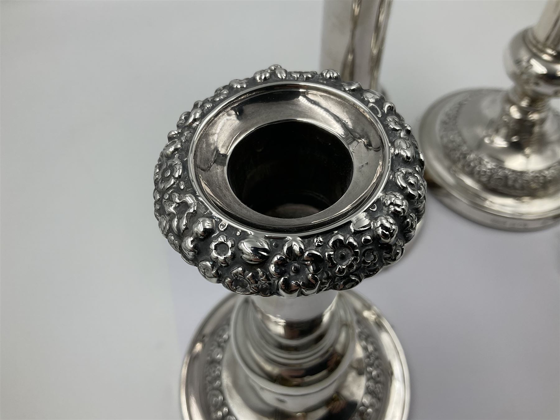 Four George III silver candlesticks, each upon knopped stem and weighted circular stepped foot, the foot and removable sconce repousse decorated with a band of flower heads, hallmarked to sconce and foot Thomas & John Settle, Sheffield 1820, H17.5cm