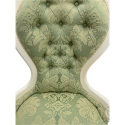Victorian style white painted nursing chair, spoon buttoned back, upholstered in pale green foliate pattern fabric