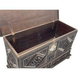 Early 20th century carved hardwood kist or mule chest of small proportions, moulded rectangular hinged lid over foliage carved geometric lozenge panels, the frame carved with chevron banding, fitted with two drawers, the drawer fronts carved with extending leaf motifs over a foliage carved lower moulding, on turned feet