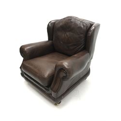 Thomas Lloyd wing back armchair upholstered in a brown leather, turned supports on castors