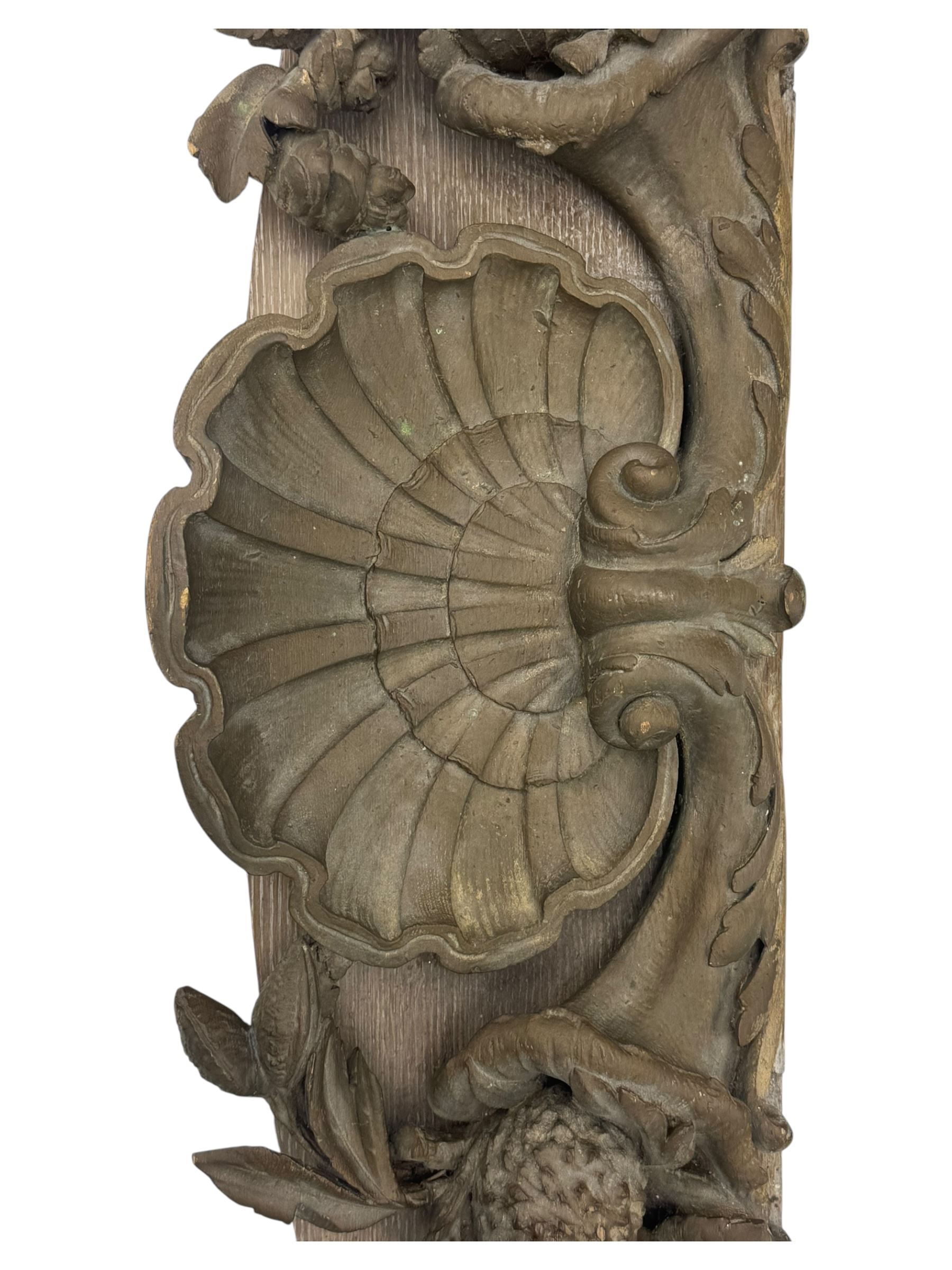 Early 20th century figural torchère, modelled as a standing putto supporting a circular top with tasselled drapery effect, raised on a circular base with foliate moulding; together with a 19th century large carved wood fragment, triangular form with high relief fruit, foliage and shell motif (H23cm, W129cm)