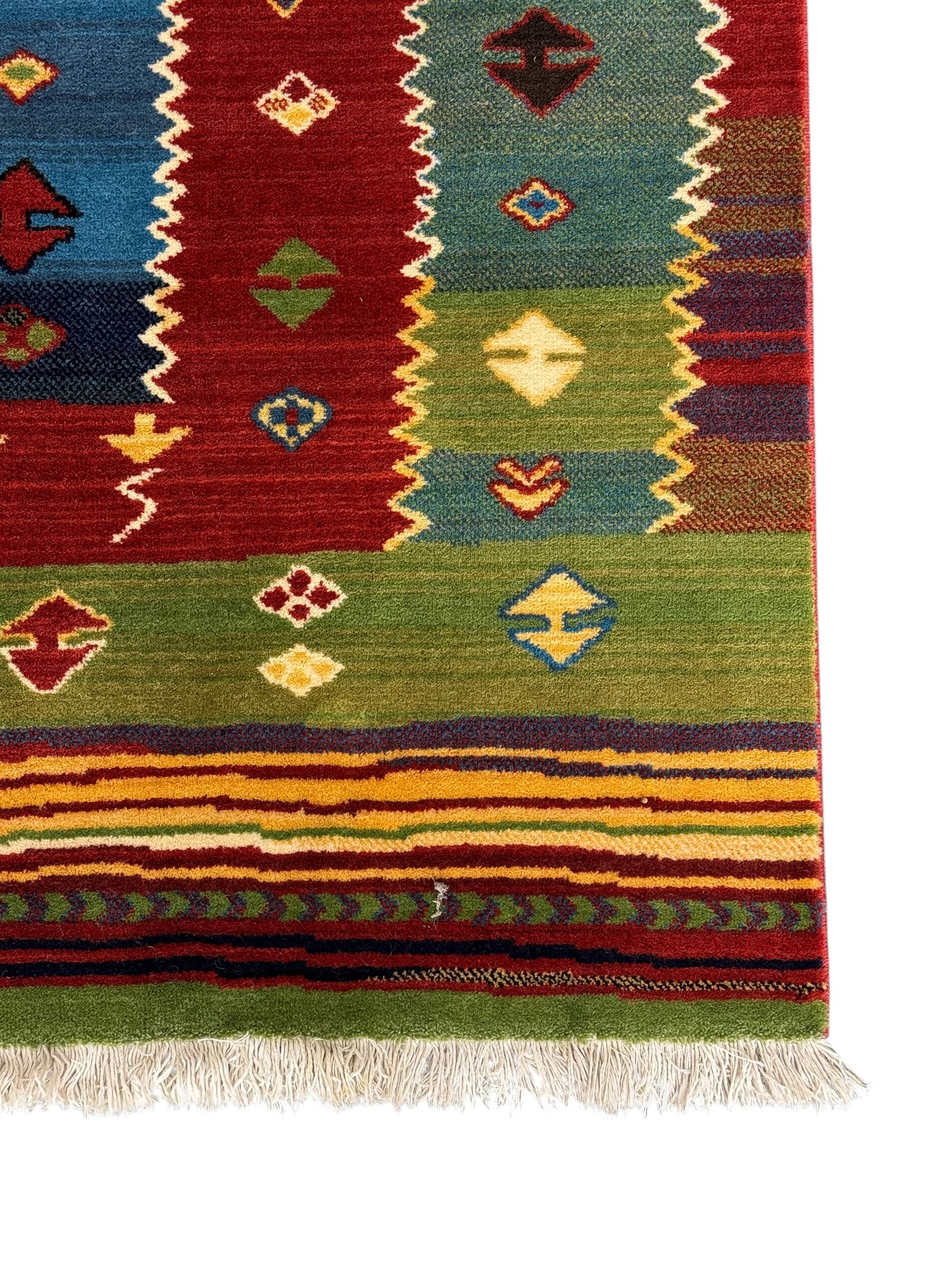 Late 20th century Louis De Poortere Belgian Shalamar wool ground rug, featuring a vibrant multi-coloured geometric design with stacked rectangular borders surrounding two central medallions, finished with fringed ends