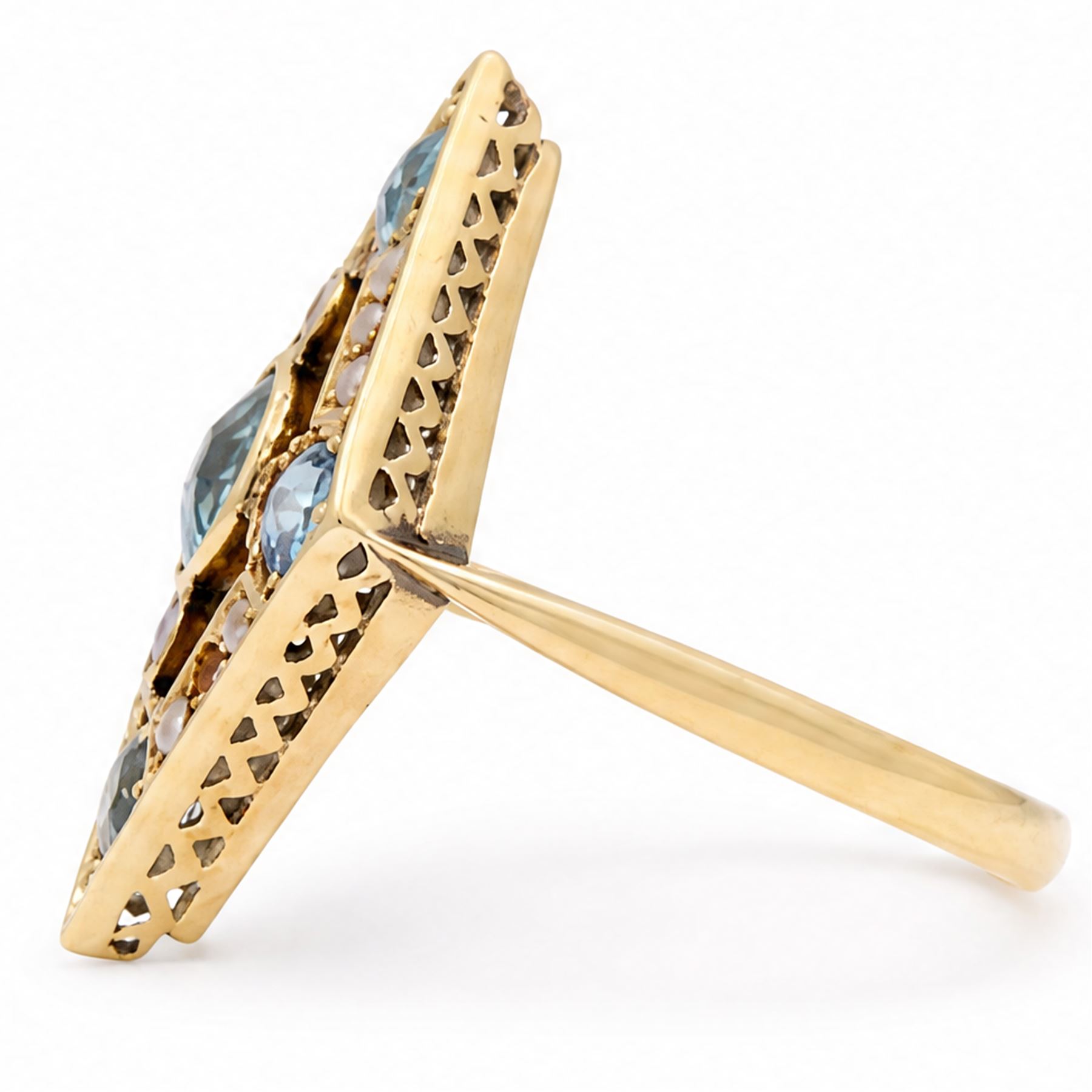 Early 20th century gold blue stone and split pearl diamond shaped ring, five milgrain set round cut stones possibly zircon or aquamarines, with seed pearl surround in a pierced design setting, stamped 18ct 