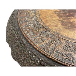 Late 19th century Anglo-Indian carved hardwood occasional table, circular tilt-top carved profusely with mythical animals and foliage decoration, pierced and carved with interlaced leafy branches, leaf carved pedestal supports on a raised platform with further carved and pierced foliage decoration, four carved feet in the form of mythical beasts with gaping jaws 