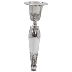 Pair of continental silver candlesticks, probably German Hanau, each of tapering form, with fern leaf decoration, upon a stepped circular base, with Hanau marks and assay scrape to base, H19cm