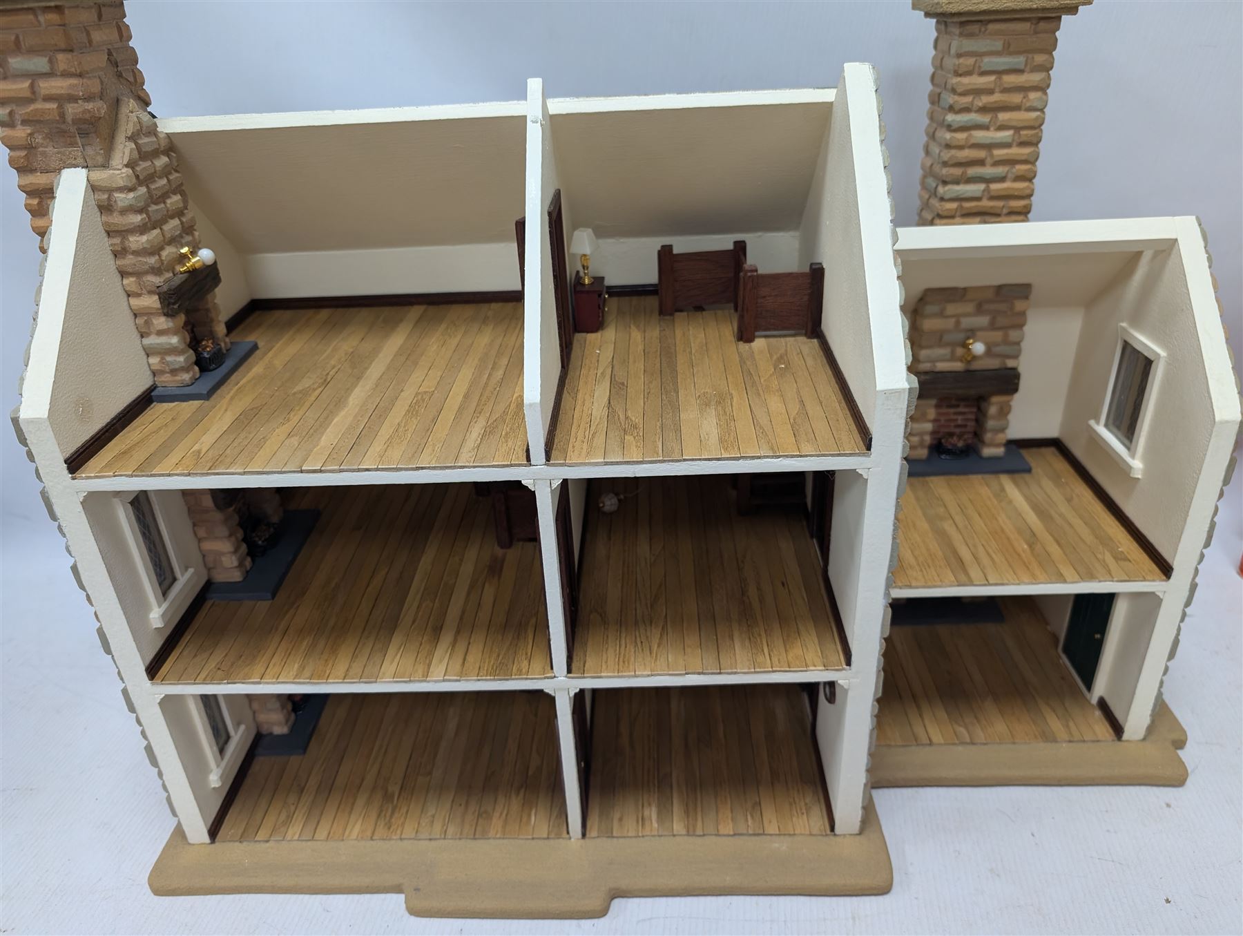 1:24 scale stone effect three-storey cottage dolls house, with green arched door and lattice effect windows, decorated to the interior with wooden floors, wired lighting and fire places, H45cm, W57cm, D26cm