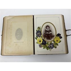  Victorian leather bound photo album, the interior leaves containing apertures of various sizes and shapes of portraits surrounded by printed floral designs, with brass clasp and painted gold decoration to edges, H30cm