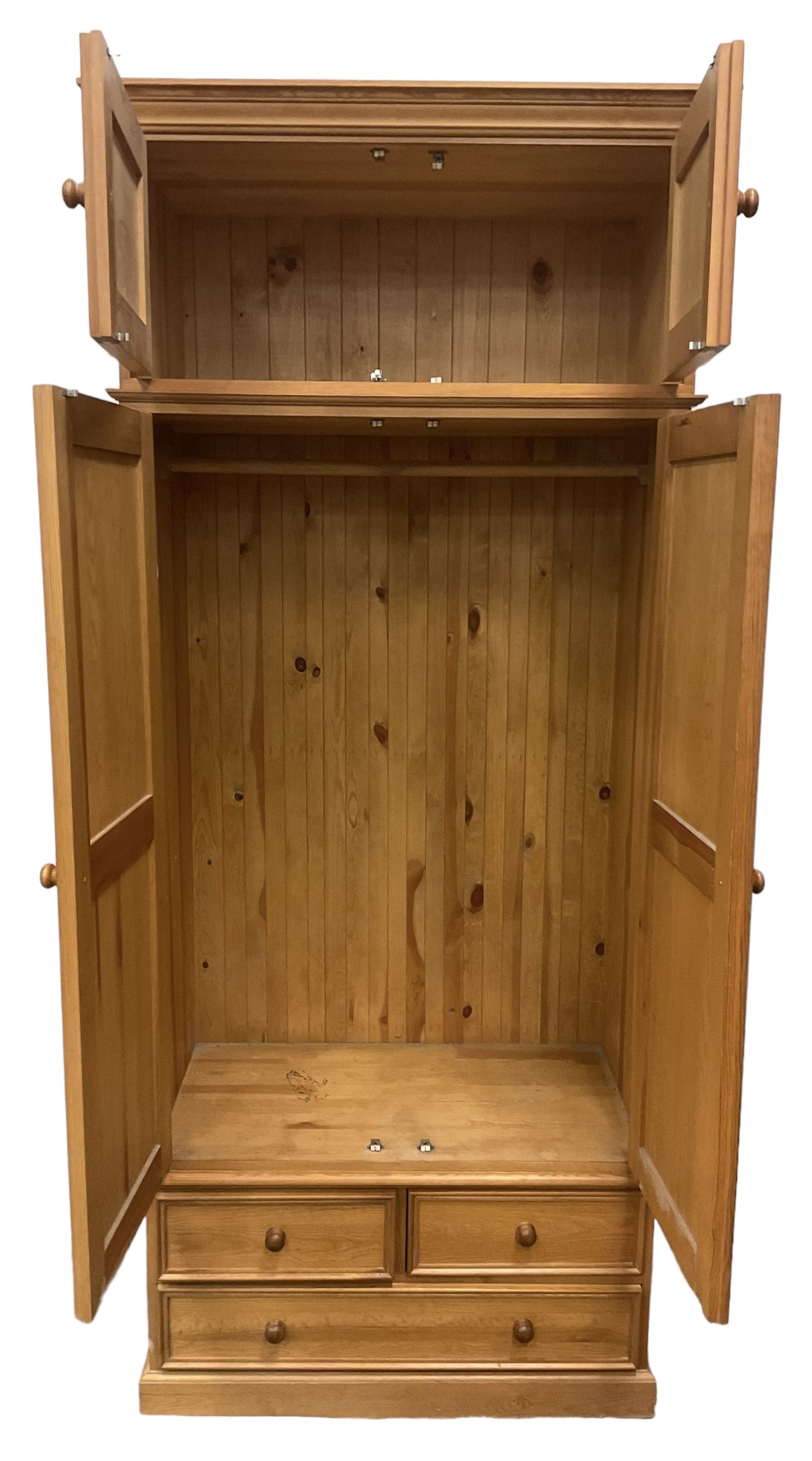 Solid pine double wardrobe, fitted with top box, enclosed by panelled doors, two short and one long drawer, on plinth base 