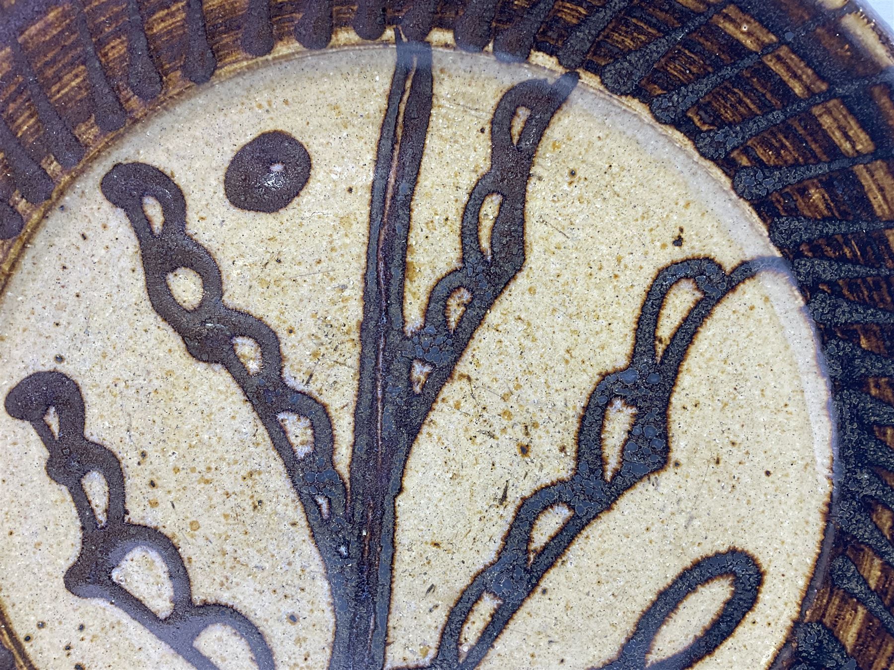 Michael Leach (British 1913-1985) for Yelland pottery; two large glazed stoneware plates with dark brown stylised decoration upon oatmeal ground, together with a jug in merging blue, green and brown, all with impressed marks beneath, largest plate D37cm