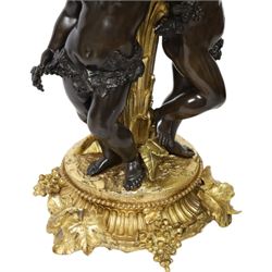 Louis XVI style gilt table lamp, the central column decorated with acanthus leaves, surrounded with three putti with vine leaf crowns, upon a circular base adorned with grape and vines, with shade, H64cm