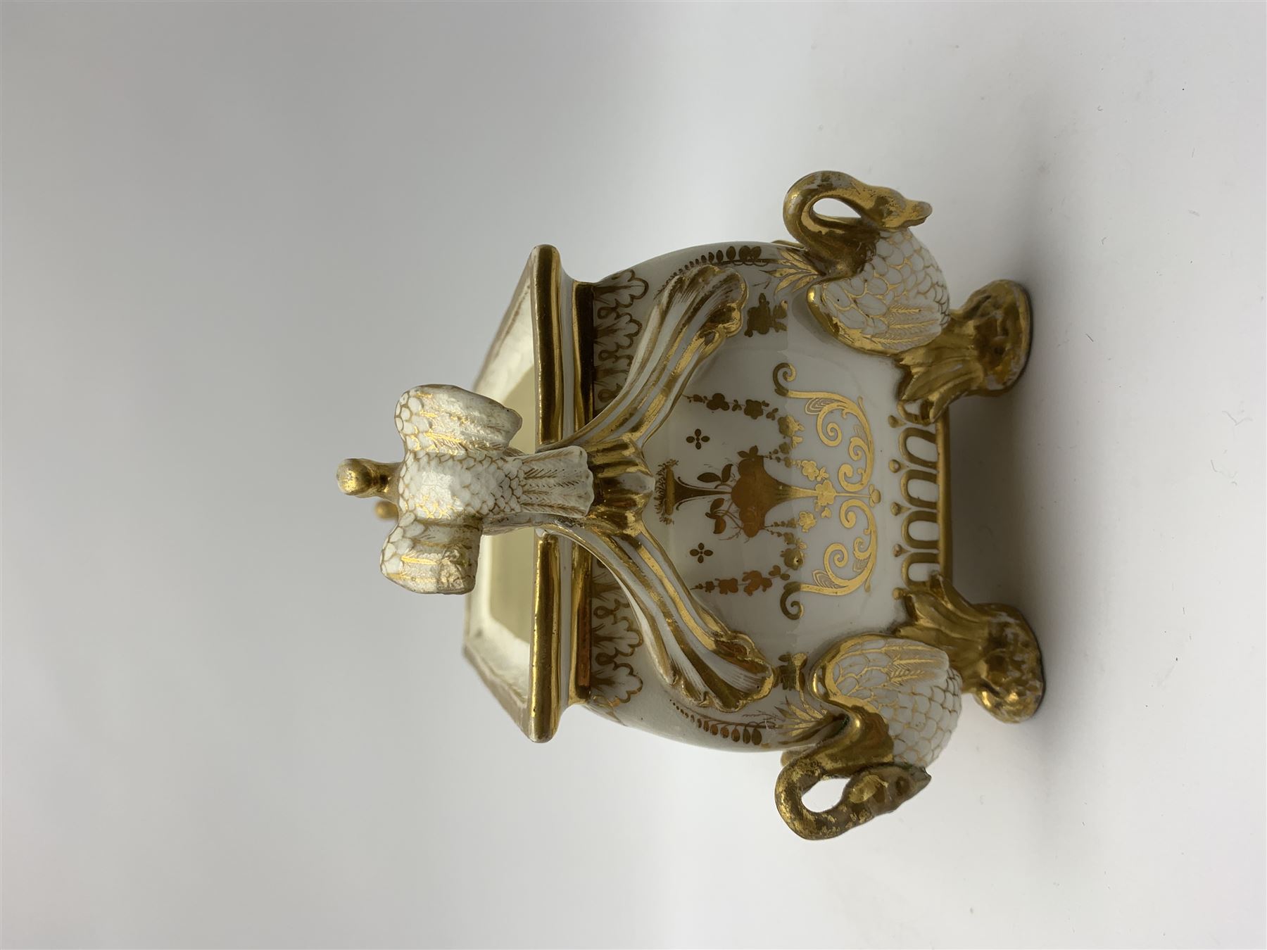 19th century Coalport bough pot, circa 1820, of bombe form, the body with twin handles surmounted by two birds and raised upon four feet modelled as swans, hand painted with two panels depicting an urn of flowers set against a mountainous landscape, the whole heightened in gilt throughout, H13cm L21cm