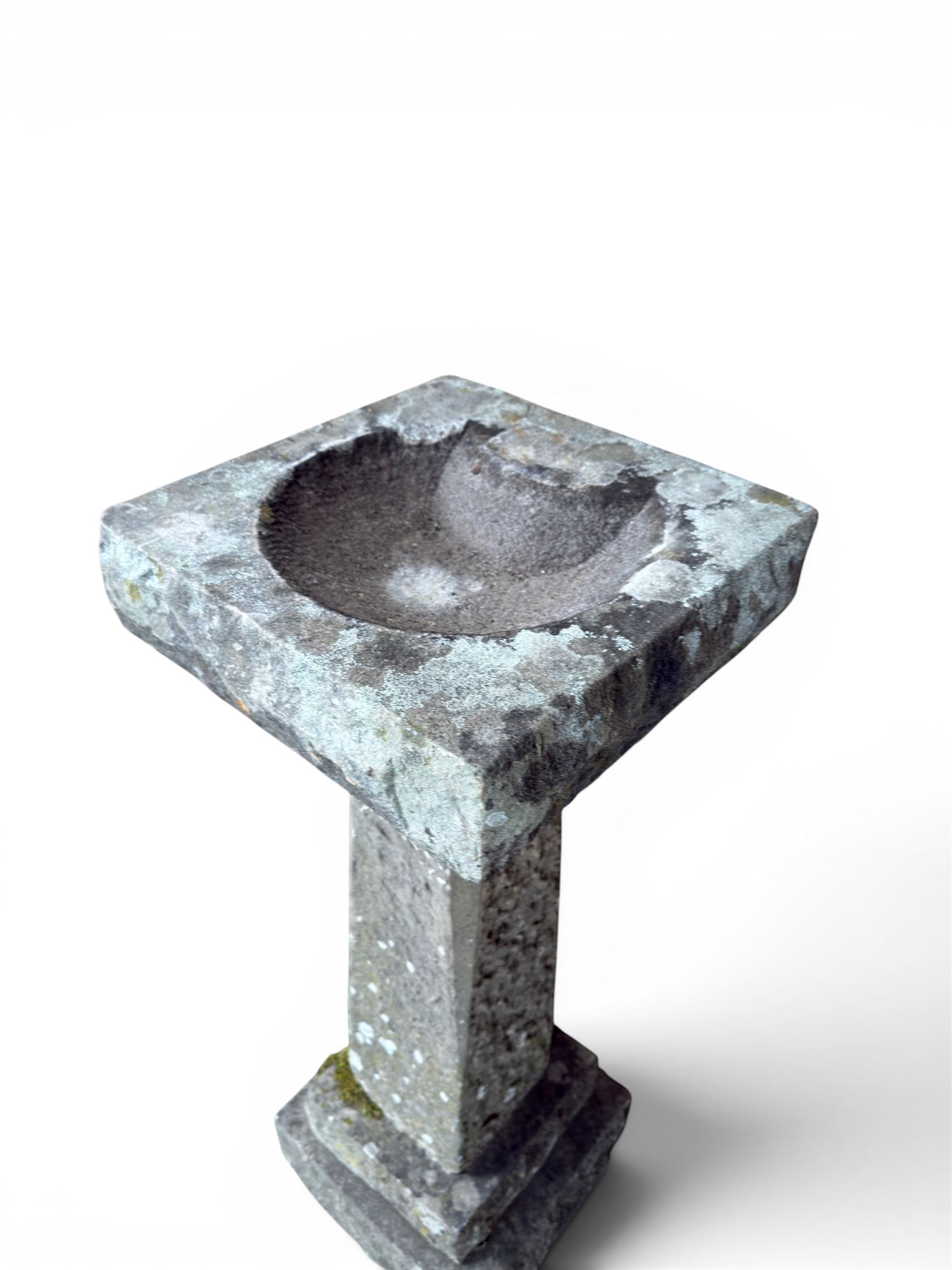 19th century weathered sandstone birdbath, formed in four sections, square top with carved shell bath, raised on tapering column with stepped base