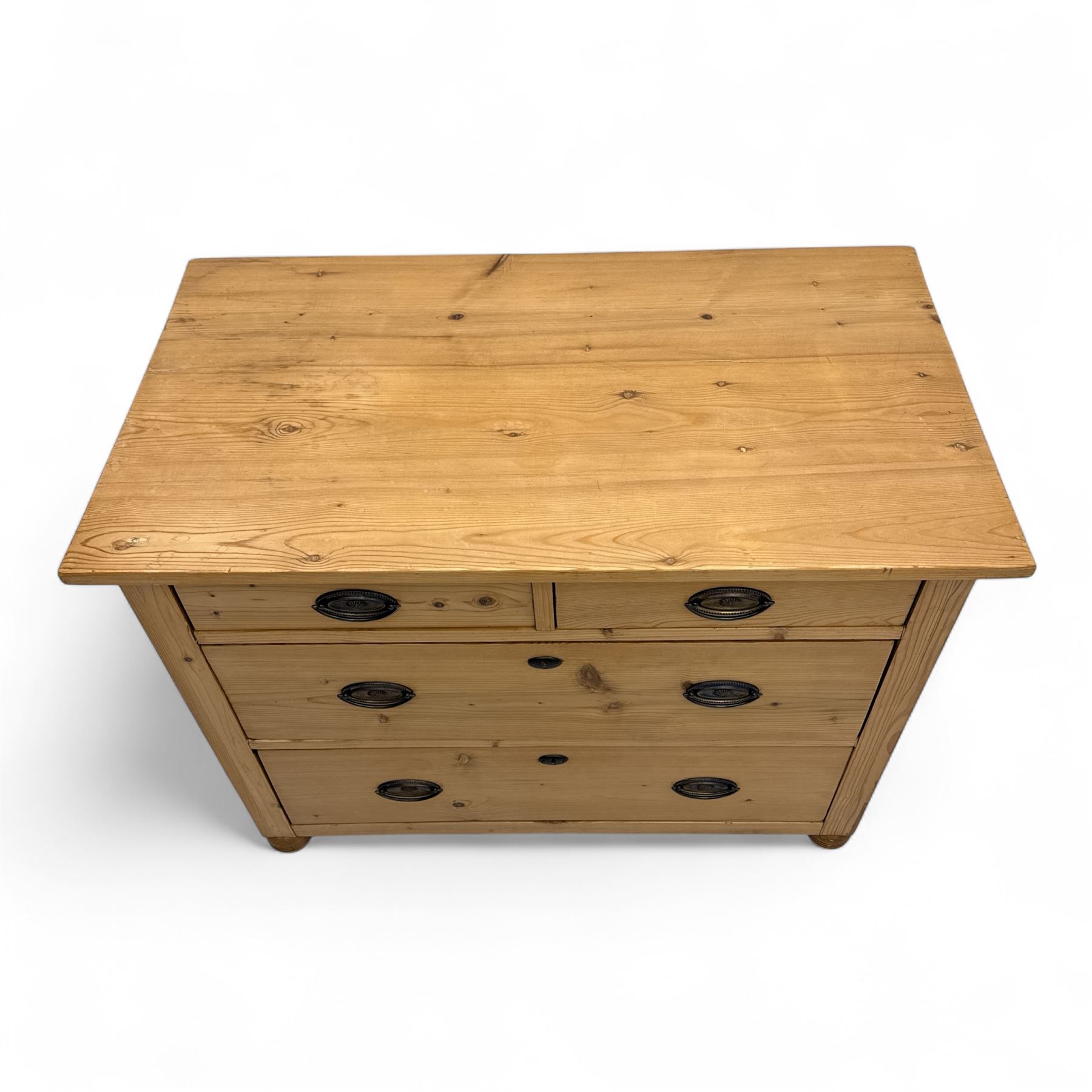 19th century pine chest of drawers, rectangular top over two short and two long drawers with oval pressed brass backplates and drop handles, panelled sides, rounded front edges, on compressed bun feet