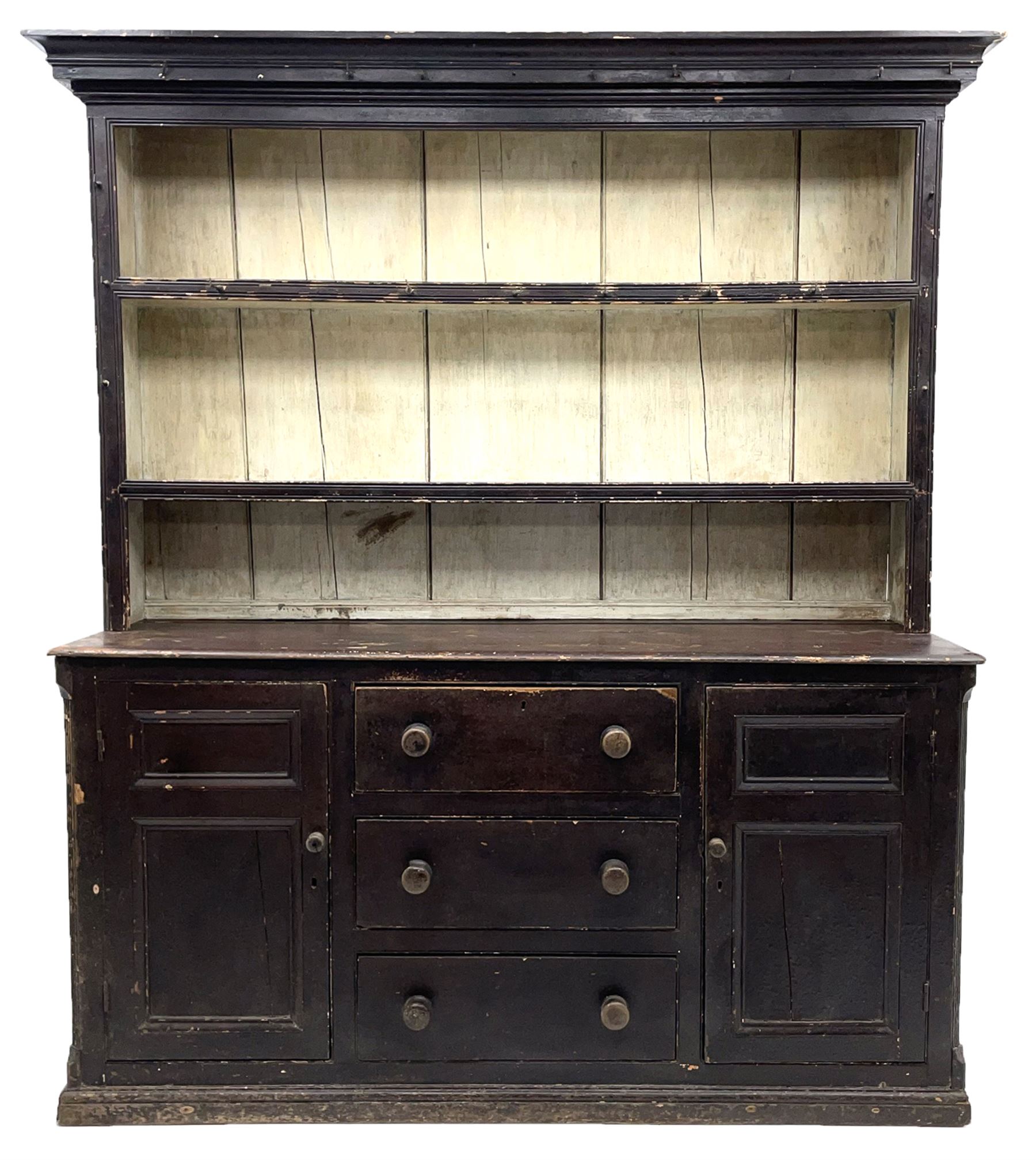 Early 19th century scumbled pine dresser, the projecting cornice over two heights plate rack with moulded frame, the base with reeded canted corners fitted with three drawers and two panelled cupboards, panelled sides, moulded skirt base