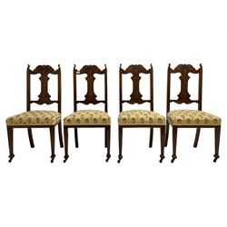 Set four late 19th century carved walnut dining chairs, the shaped cresting rail carved with foliage scrolls, upholstered seats in floral design fabric, square tapering supports with compressed spade feet, on brass and ceramic castors