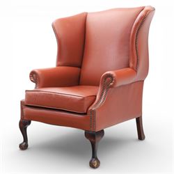 Georgian design red leather wingback armchair, with shaped back and scrolled arms, and close brass studded trim, upon cabriole front legs with claw and ball feet