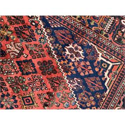 Persian Joshgan red ground rug, the medallion, field and spandrels decorated with clusters of Pitrak and tree of life motifs, the border with repeating design decorated with stylised plant motifs, within guard stripes