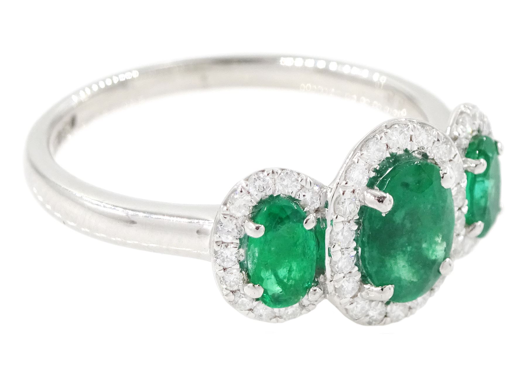 Platinum emerald and diamond trilogy ring, three oval cut emeralds surrounded by round brilliant cut diamonds, hallmarked, total emerald weight approx 1.05 carat, total diamond weight approx 0.25 carat
