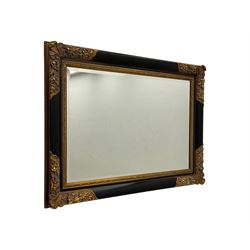 Early 20th century wall-hanging mirror, rectangular bevelled mirror plate within ebonised frame, gilt mounts to the corners carved with floral motifs 