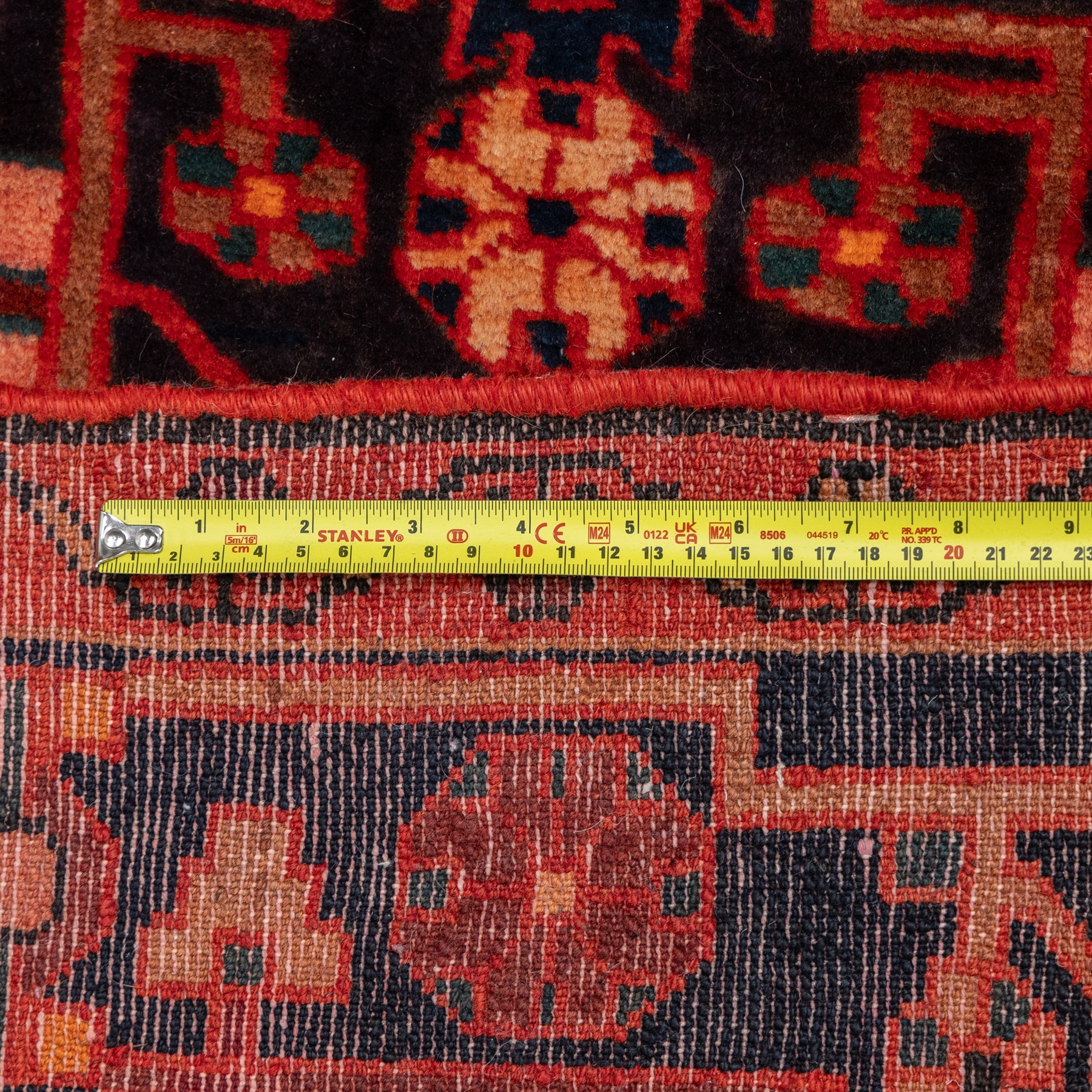 North West Persian runner, the indigo field centred by a red elongated hexagonal medallion with pendant motifs, surrounded by angular flowering stems, ivory stepped floral spandrels, enclosed by an indigo palmette border and red floral guard bands