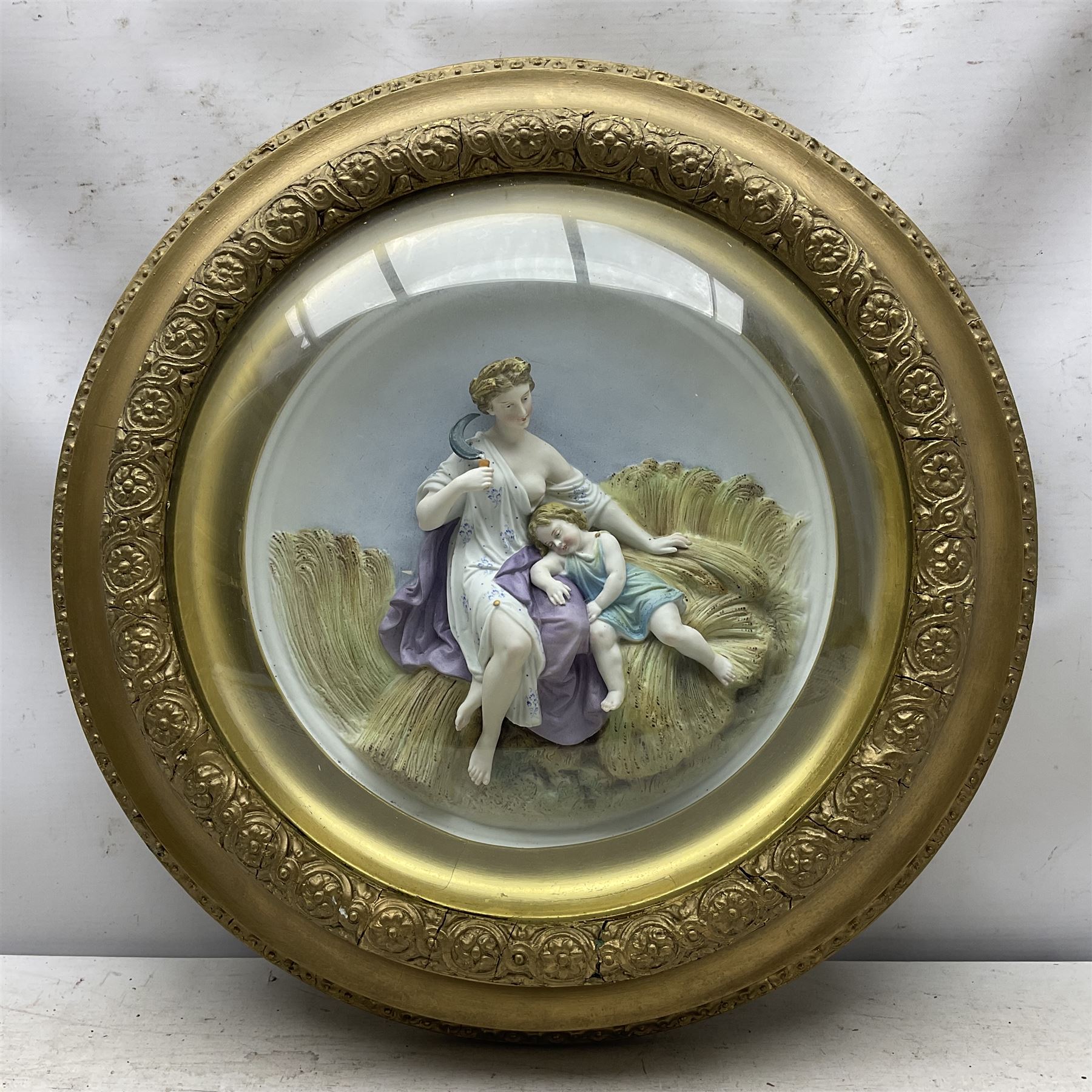 Set of four early 20th century Continental bisque plaques, each of circular form, modelled in high relief as the Four Seasons personified, within gilded circular frames under convex glass, overall D44.5cm