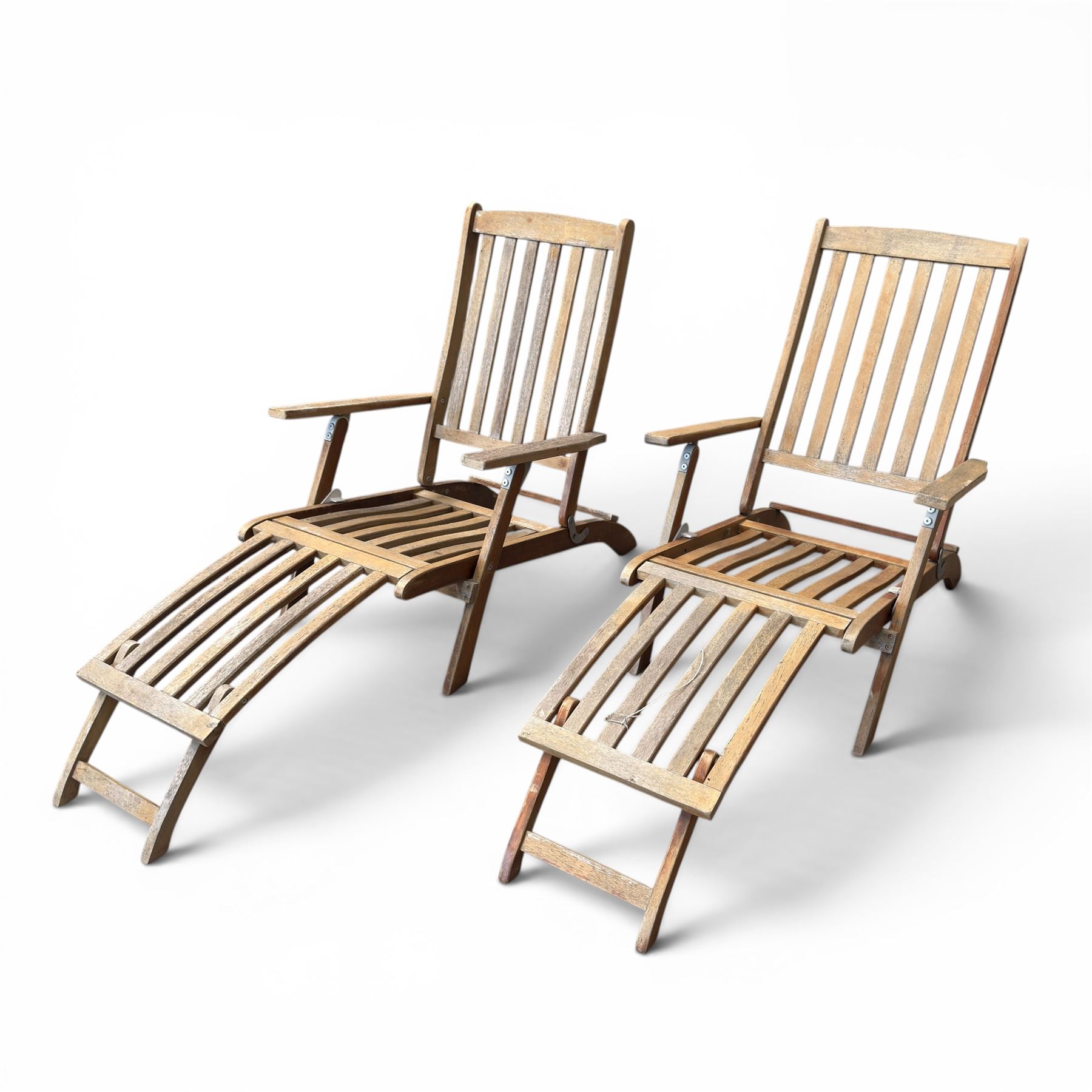 Pair of teak folding steamer chairs, with slatted backs, seats and extending footrests, adjustable recline.