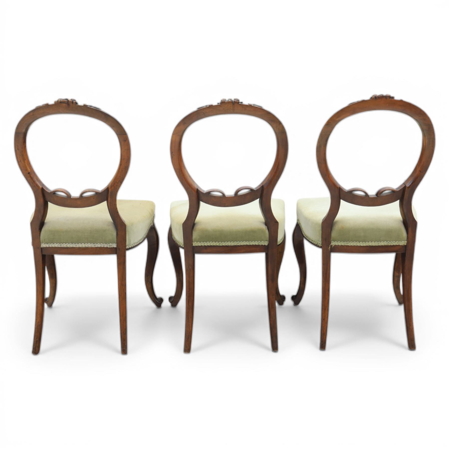 Victorian mahogany dining suite, oval tilt top dining table raised on a quatriform base with paw feet, together with a set of six balloon back dining chairs with green upholstery with cabriole legs 