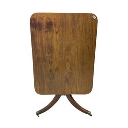 Regency mahogany tilt-top salon table, rectangular top with rounded corners, raised on turned pedestal with splayed tripod base and brass cups and castors