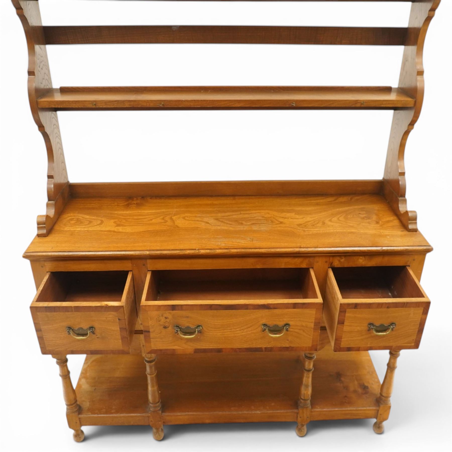 Georgian design elm dresser with plate rack, the two-tier rack with shaped frieze and hooks, over a rectangular top, fitted with three yew-wood banded drawers, shaped apron over turned supports united by undertier
