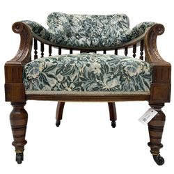Victorian walnut framed tub-shaped armchair, the shaped rolled back supported by a spindle turned balustrade, upholstered in buttoned floral fabric, scrolled arms supports carved with acanthus leaves and flower heads, on collar turned feet with brass and ceramic castors