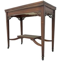 Edwardian inlaid mahogany games table, the rectangular fold-over swivel top decorated with central shell motif inlay and ebony stringing, raised on tapering supports united by shaped X-stretcher and undertier