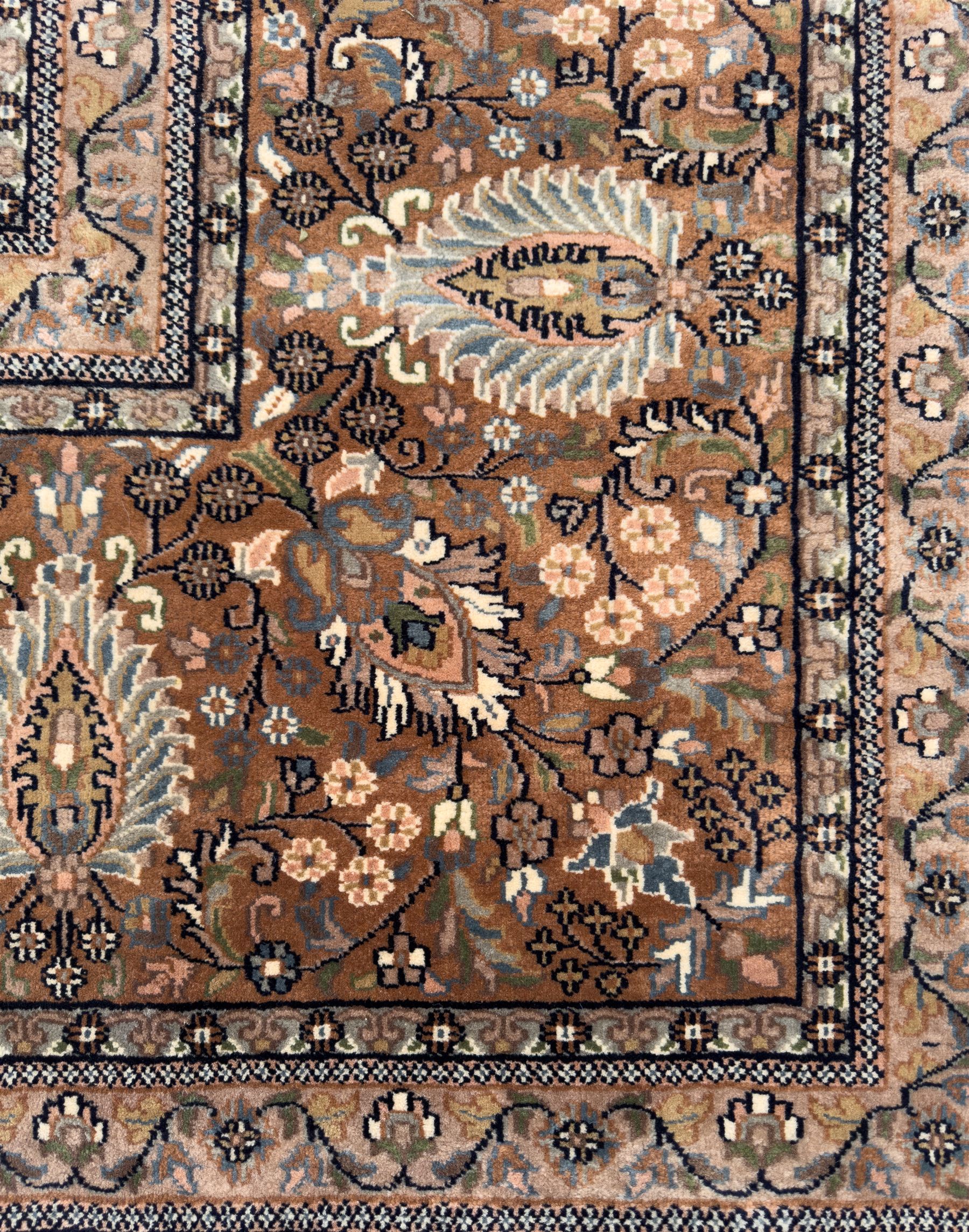 Large Persian indigo ground rug, the busy field decorated with trailing branches and flower heads, peach border decorated with palmettes -
