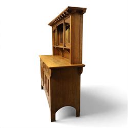 Art Nouveau oak mirrored sideboard, in the manner of Liberty's London, the raised back fitted with bevelled mirror plates divided by turned supports beneath a projecting cornice, above two drawers and panelled cupboard doors, the central panel applied with stylised floral carved panel, raised on shaped feet