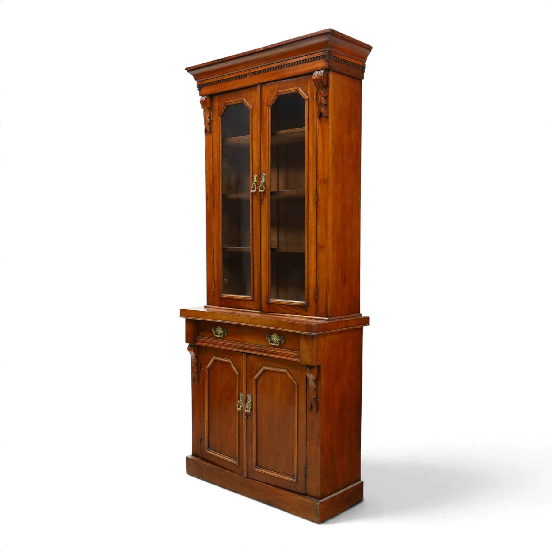 Victorian mahogany bookcase on cupboard of slender proportions, projecting cornice over dentil-frieze, fitted with twin-glazed doors enclosing three shelves, flanked by acanthus corbels, the base fitted with single frieze drawer over panelled cupboard, on skirted base