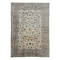 Persian Kashan Ivory ground carpet, the busy field decorated all over palmettes and trailing branches, scrolling border interspersed with stylised plant motifs, within guard stripes