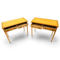 Pair of George III design inlaid satinwood console or side tables, rectangular top with mahogany cross-banding and ebony stringing, fitted with two drawers with brass ring handles, on square tapering supports with brass cups and castors