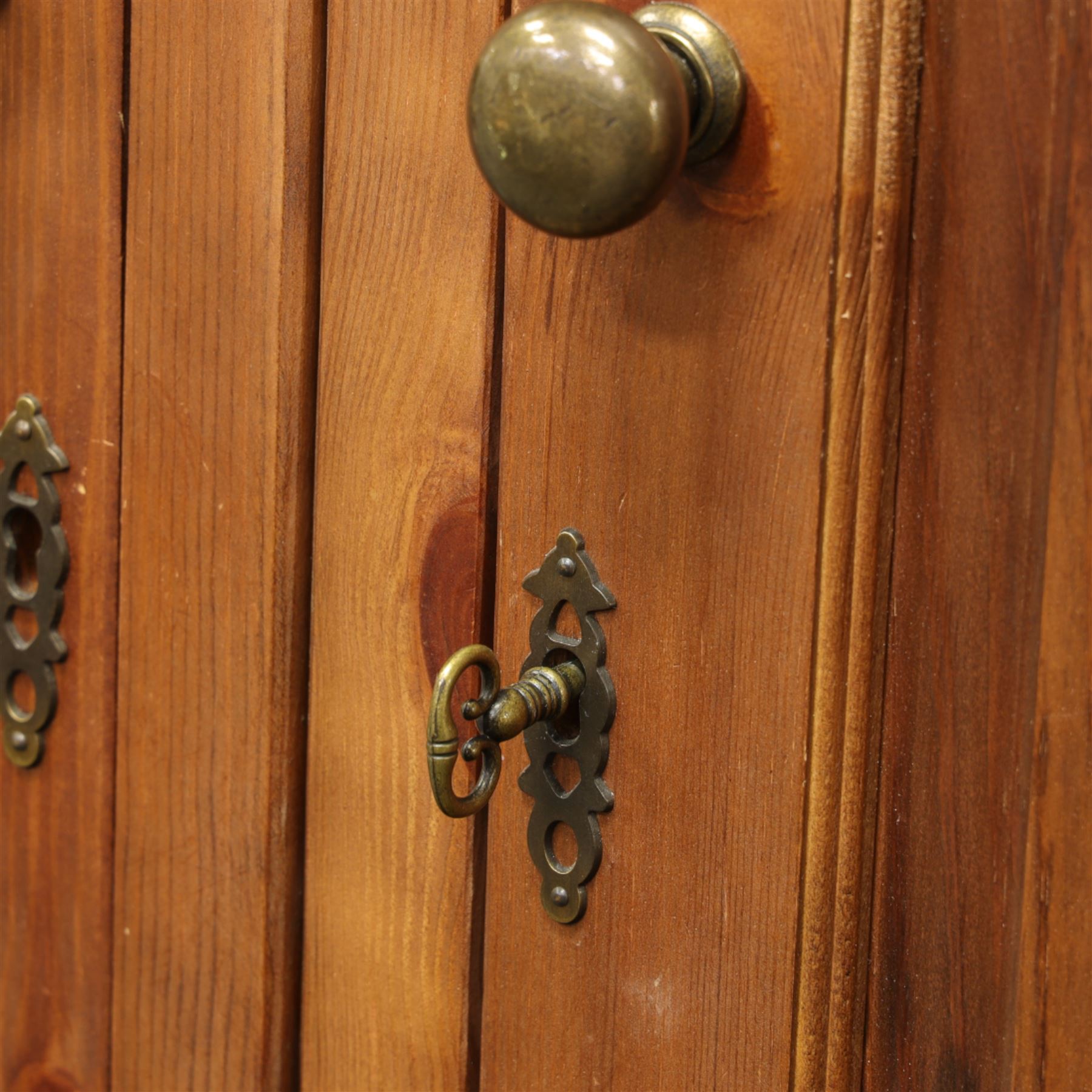Traditional design contemporary dark stained pine double wardrobe with top box, twin three panelled door with wooden studded frieze, enclosing a single metal rail, with a top box above with brass handles