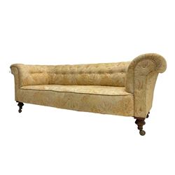 Early 20th century Chesterfield sofa, upholstered in buttoned coral and beige foliate patterned fabric with sprung seat, raised on turned supports with castors