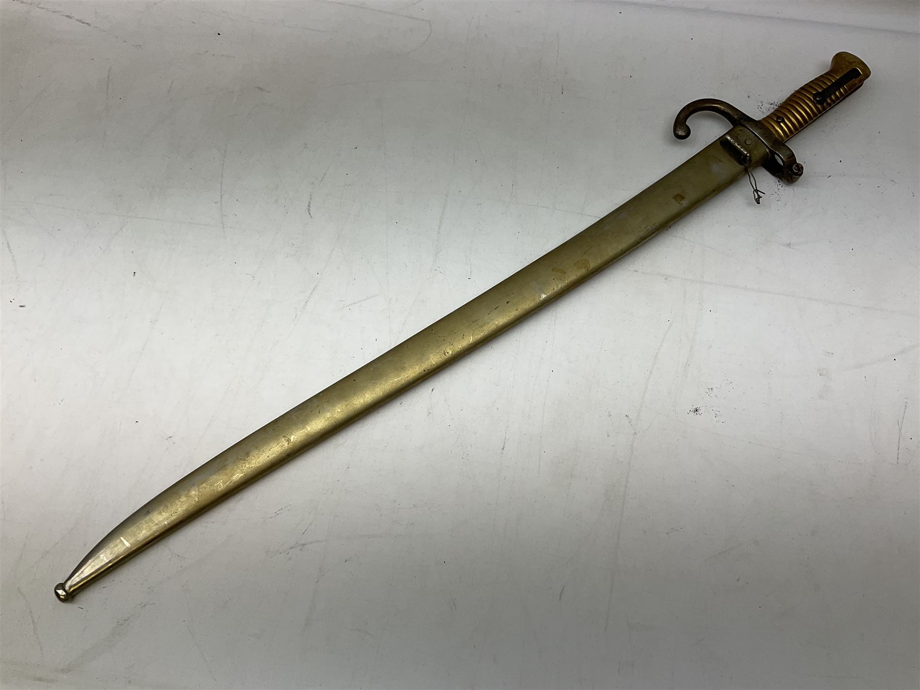 French Model 1866 sabre bayonet with 57cm fullered steel curving blade; in steel scabbard L71cm overall; another Model 1866 sabre bayonet lacking scabbard; and British Pattern 1856 sword bayonet (no scabbard) (3)