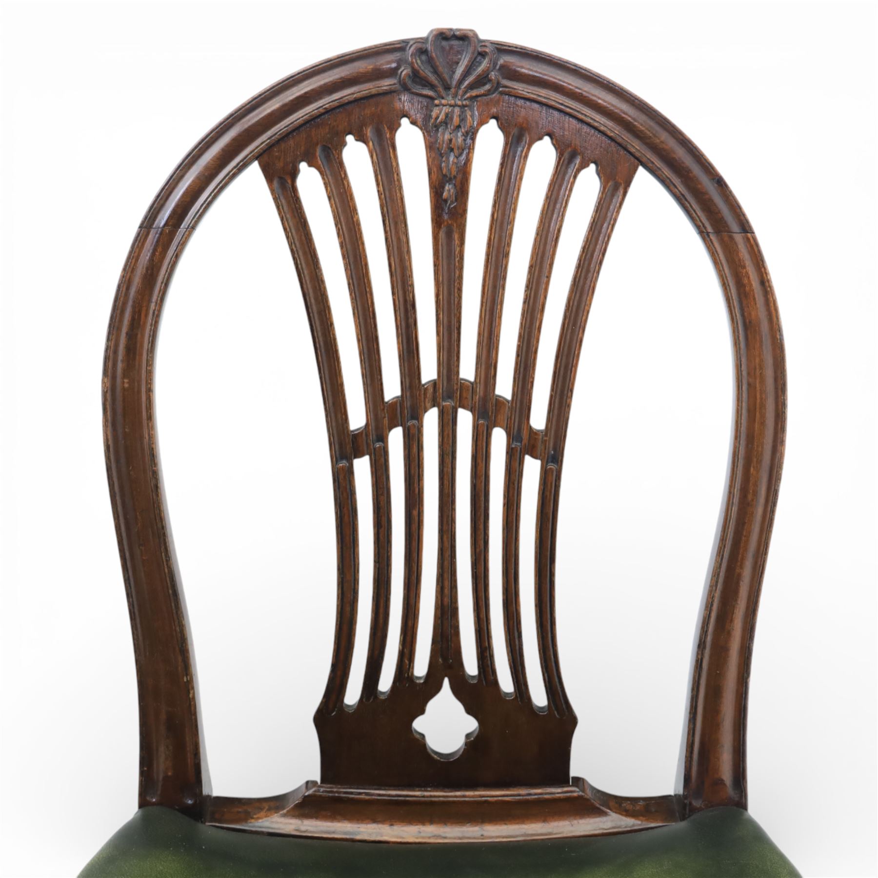 George III style set of six mahogany dining chairs, the arched backs with pierced and carved vase splats beneath carved husk and patera detail, drop-in upholstered seats covered in green leather with brass studded edging, raised on square section legs united by plain stretchers