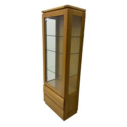 Light oak illuminated display cabinet, enclosed by bevelled glazed door, fitted with three adjustable shelves, two drawers below