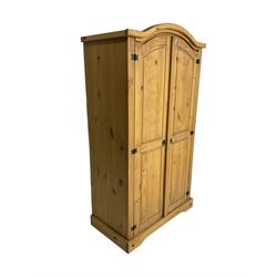Pine double wardrobe, arched top, enclosed by two panelled doors on a plinth base