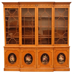 Sheraton Revival satinwood breakfront bookcase, frieze painted with scrolling leafage above four astragal doors with adjustable shelves, the base with four doors painted with floral sprays in oval panels, on a plinth base, W234cm, H235cm, D52cm