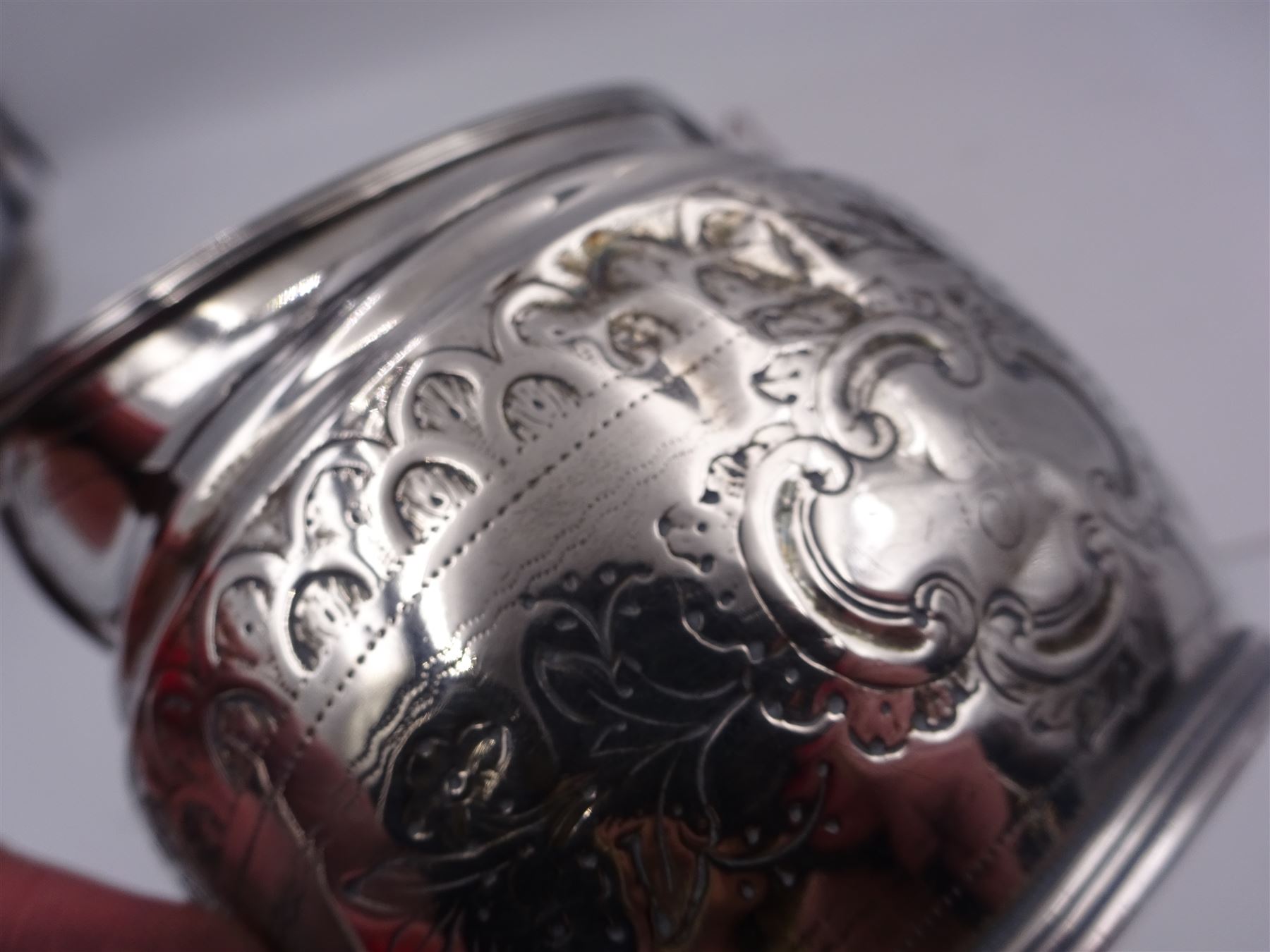 George III silver cream jug, of helmet form with angular handle, embossed with floral and scrolling decoration and engraved initial, hallmarked Edward Mayfield, London 1806, H9.3cm, together with a modern silver 'Sherry' decanter label, hallmarked Birmingham Mint, Birmingham 1986
